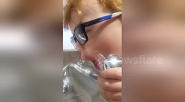 Boy struggles to drink from fountain