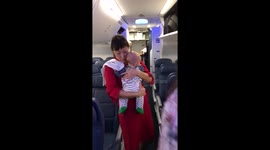 Flight attendant holds baby to help parents settle in plane