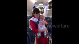 Newsflare Edit - Flight attendant holds baby to help parents settle in plane