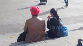 A ladies eating a sandwich like the pigeons in Trafalgar Square