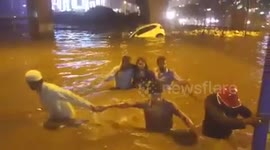 Locals pull woman from car which was sinking in flash floods