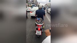 Helmet-wearing cat rides motorcycle with owner
