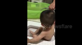 Father gives shower to his son in a urinal