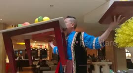 Man lifts table with full of dishes by his mouth, while dancing to music
