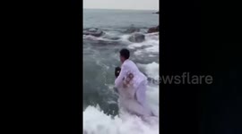 Head over heels: Newlyweds floored by wave during photo op