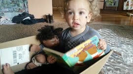 Toddler in Box Reads to Babydoll