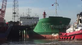 Tugs on move to help ship off jetty on Thames at Grays, Essex