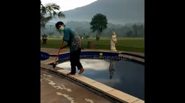 Balinese man sweeping up volcanic ash during volcano eruption.