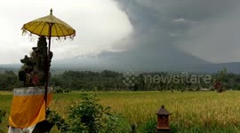 Mount Agung Bali Volcano erupting by rice fields and house god.