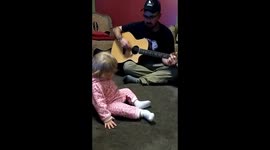 Baby dancing while daddy plays guitar