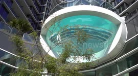 Swimming pool hangs over sidewalk with glass bottom.  Swimmers feel like they're floating.