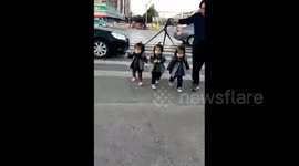 Grandfather holds triplets with leads to cross road
