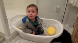 Little boy hops in bath with clothes on