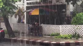Two enjoy meal under umbrella through monsoon