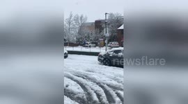Man slips and falls as he pushes a car in the snow