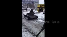 Man drives toy tank on snow-covered road