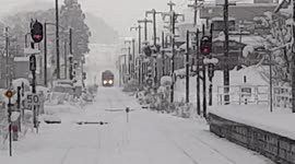 Snowing scene, train stopped on snow cover railway track waiting for opposite direction train to pass on shared track.