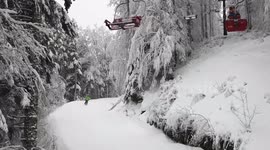Going up on a chair lift in mountains in the middle of snowy wood