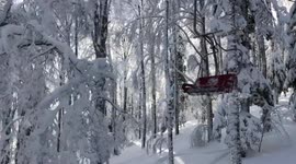 Going up on a chair lift in mountains in the middle of snowy wood