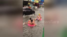 British tourists play on inflatable rubber rings in flood
