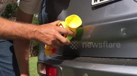 Husband attempts to fix dent in his wife's car using a bath toy.
