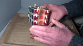 Man plays with burning candle Rubik's Cube