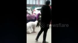 Woman crawls on all fours next to fiancé on busy street in China