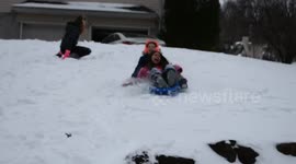 Girls sled over boulders, laughing