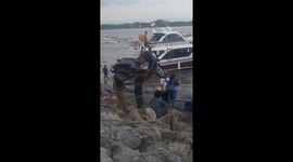 Man carries his moped onto boat
