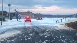 Woman gets soaked as a wave whips up sea foam - Storm Emma