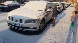 Boy clears snow off car