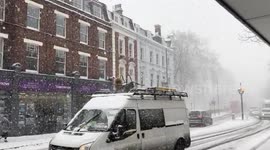Snow falling and slow traffic in Islington, London