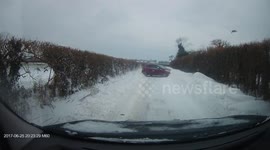 Car driving down snow-covered UK road loses control