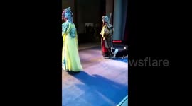 Dog tugs on Chinese opera performer's costume while on stage