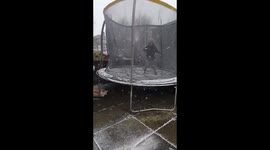 lad age 7 playing on the trampoline in the snow slips over