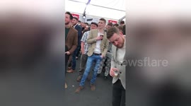 Newsflare Edit - Man dives through pyramid of cups in music tent at Cheltenham racecourse during The Cheltenham Gold Cup Festival