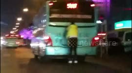 Man on roller skates holds on to back of moving bus
