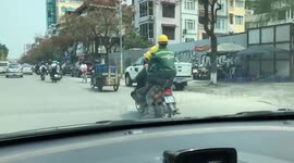 Five men sit on a motorbike moving on the city road