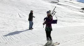 Female skiing down Glenshee ski centre while playing bagpipes