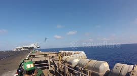 Helicopters and squadron of fighter jets fly past US aircraft carrier