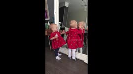 Twin girls discovering their reflections in the mirror and loving them