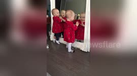 Adorable twins play with reflections in mirror