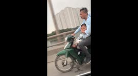 The man carrying his son on the motorbike while the baby is sleeping