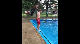Parkour-gymnast dives over friend standing beside pool