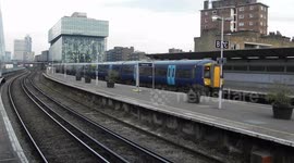 Train leaving station with train crossing over top with the Shard building in the destance