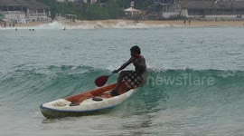 Fisherman knocked off his boat by passing wave at Mirissa Beach, Sri Lanka