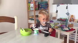 Baby eats yoghurt with hands