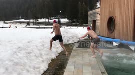 Two handsome young men get out of a hot pool and dive into snow