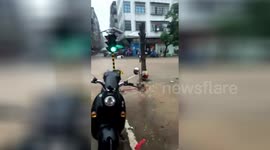 Watch a traffic light get swept down the street by flood waters in China