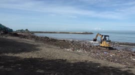 Heavy equipment clean plastic waste on the beach